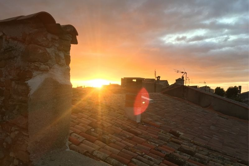 A view of the sun setting over the tile roofs of buildings in a small village in the south of France