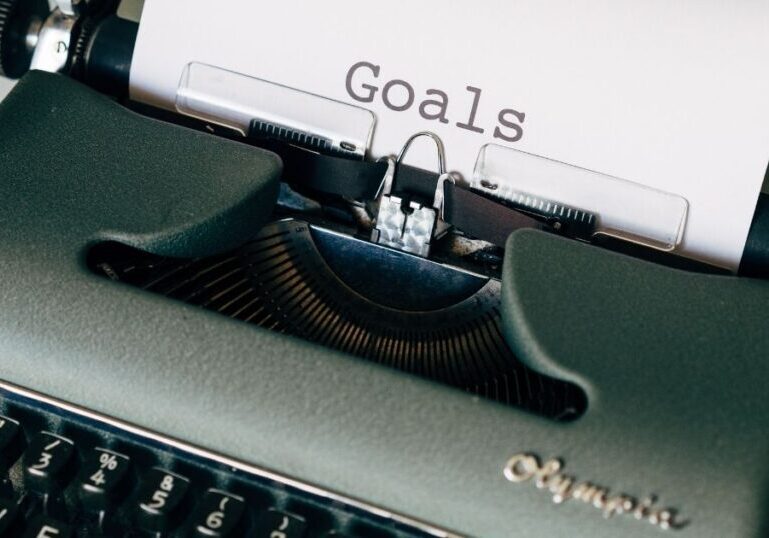 Green Olympia typewriter with paper in carriage and the word "Goals" typed on the page